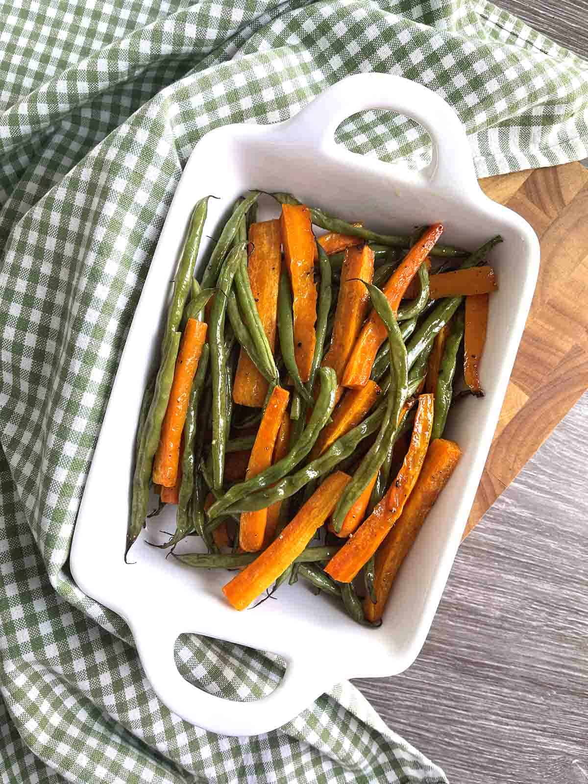 roasted green beans and carrots in a dish.