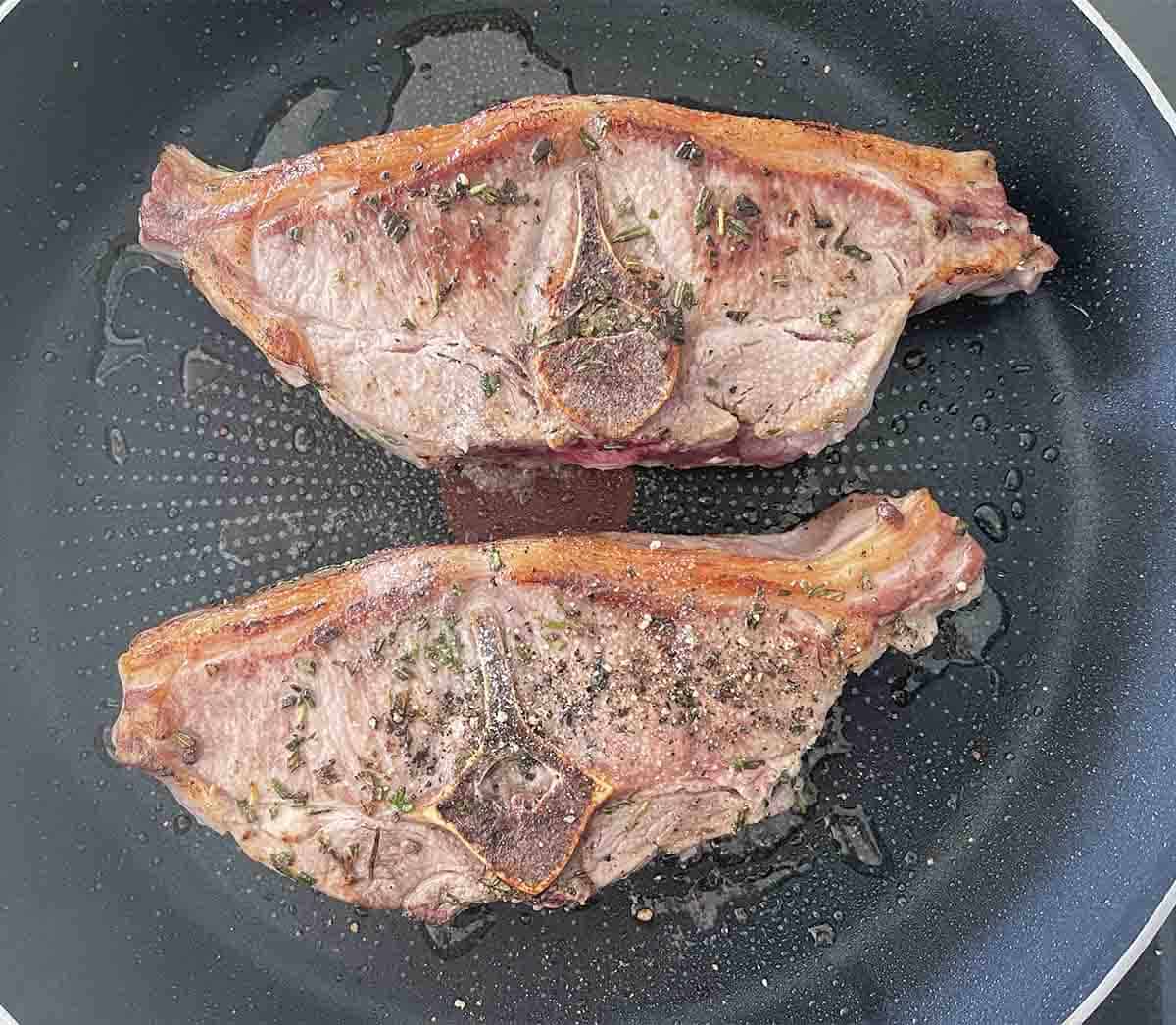 chops frying in a pan.