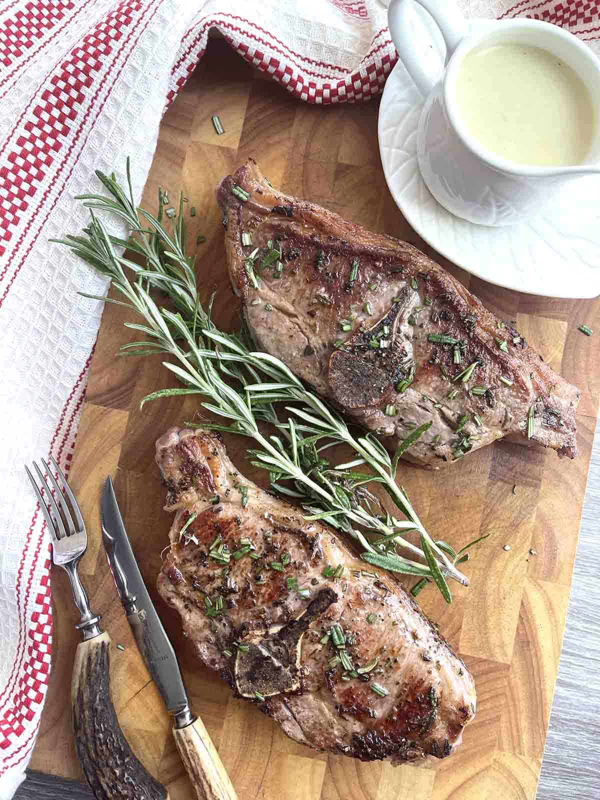 pan fried lamb chops on a board with sauce.