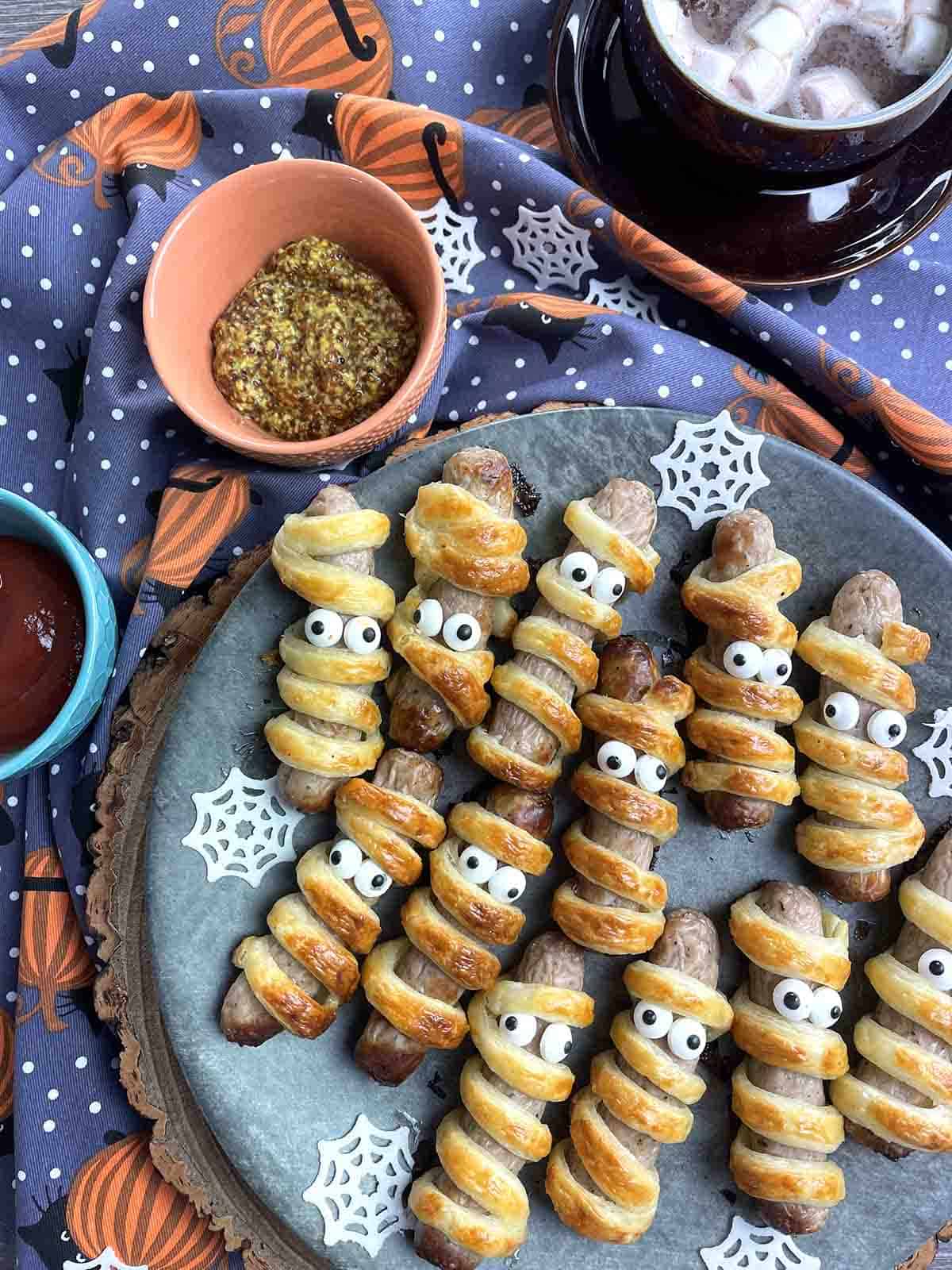 mummy sausage rolls on a plate.
