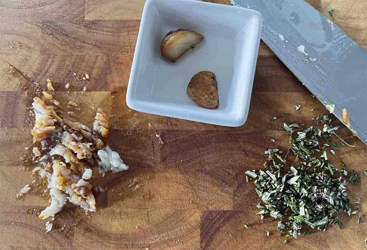 chopped garlic and rosemary on a board.