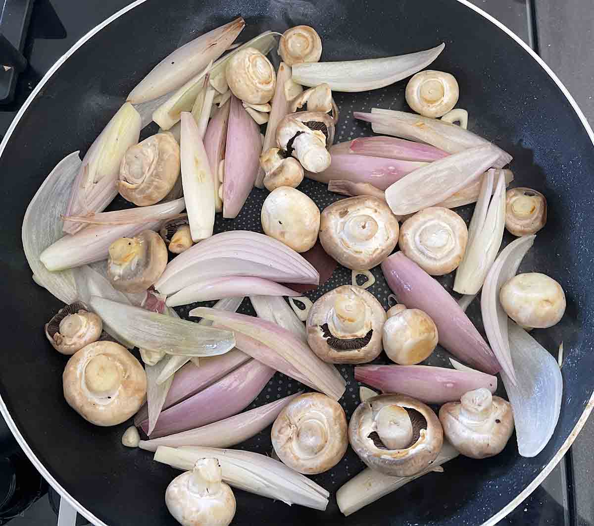 shallots and mushrooms in a pan.