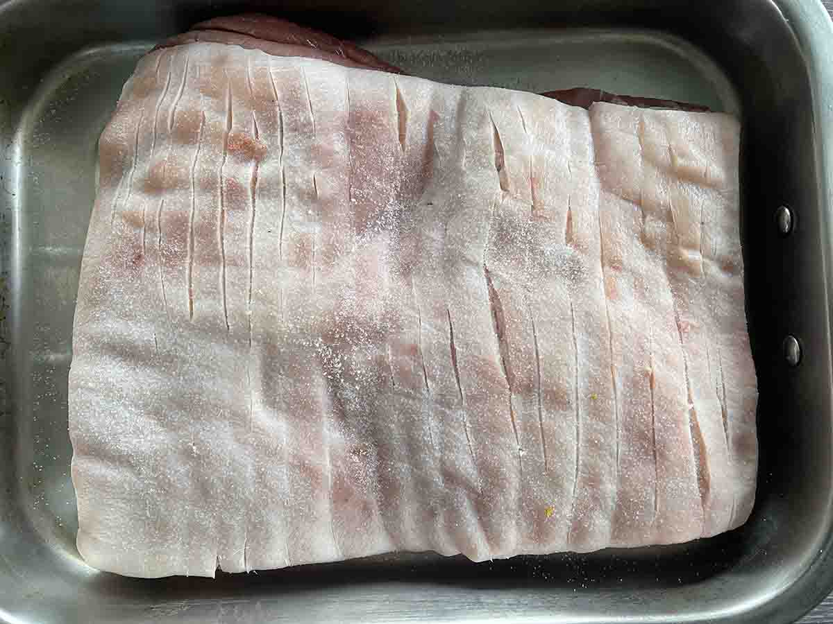 scored pork in a roasting dish.