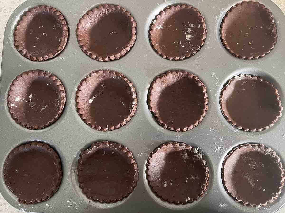 patty tins lines with chocolate pastry dough.