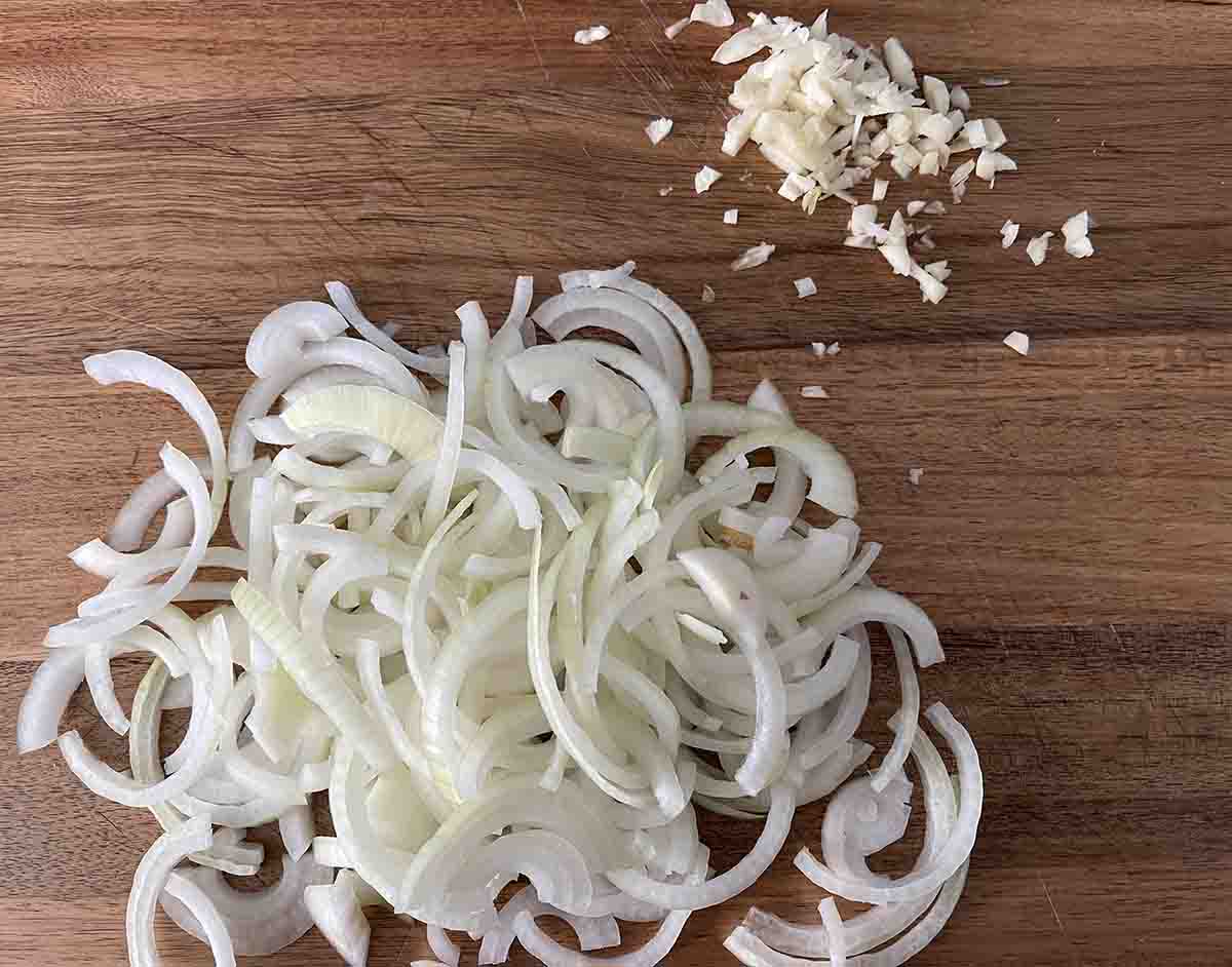 sliced onions and chopped garlic on a board.