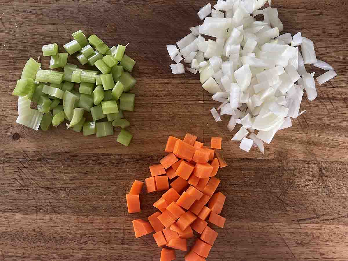 chopped celery, onion and carrot on a board.