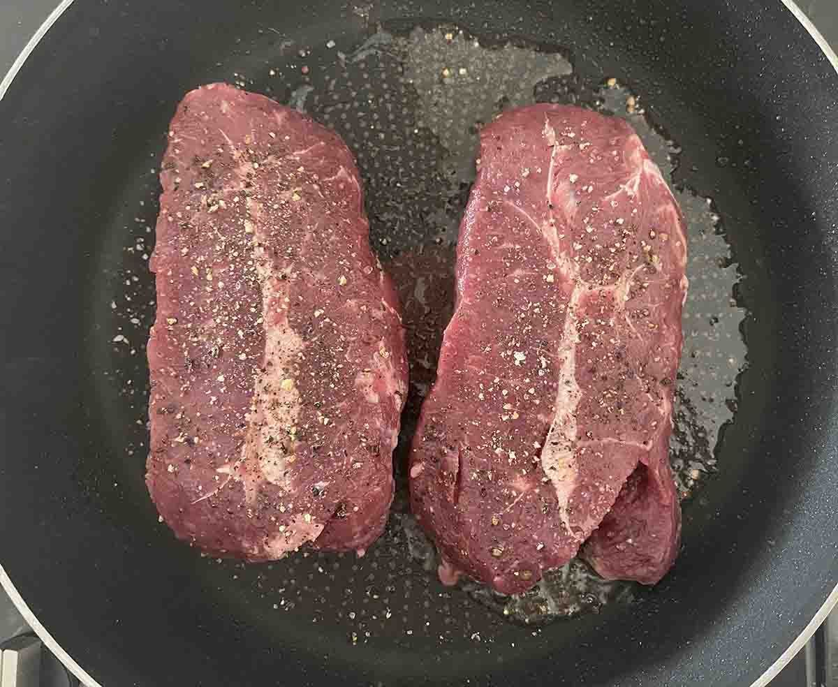 seasoned steaks in the pan.